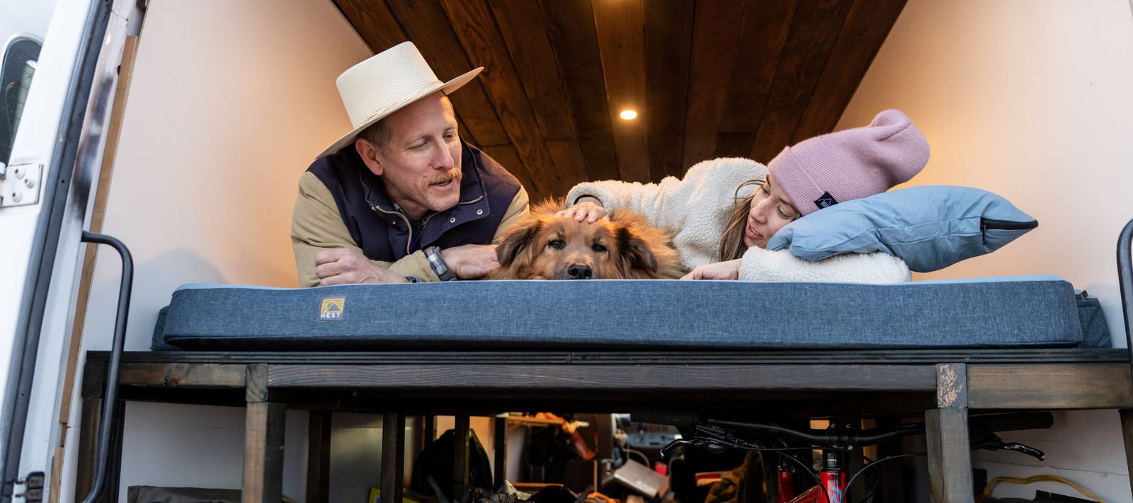 Two people laying on a HEST camping mattress in their van